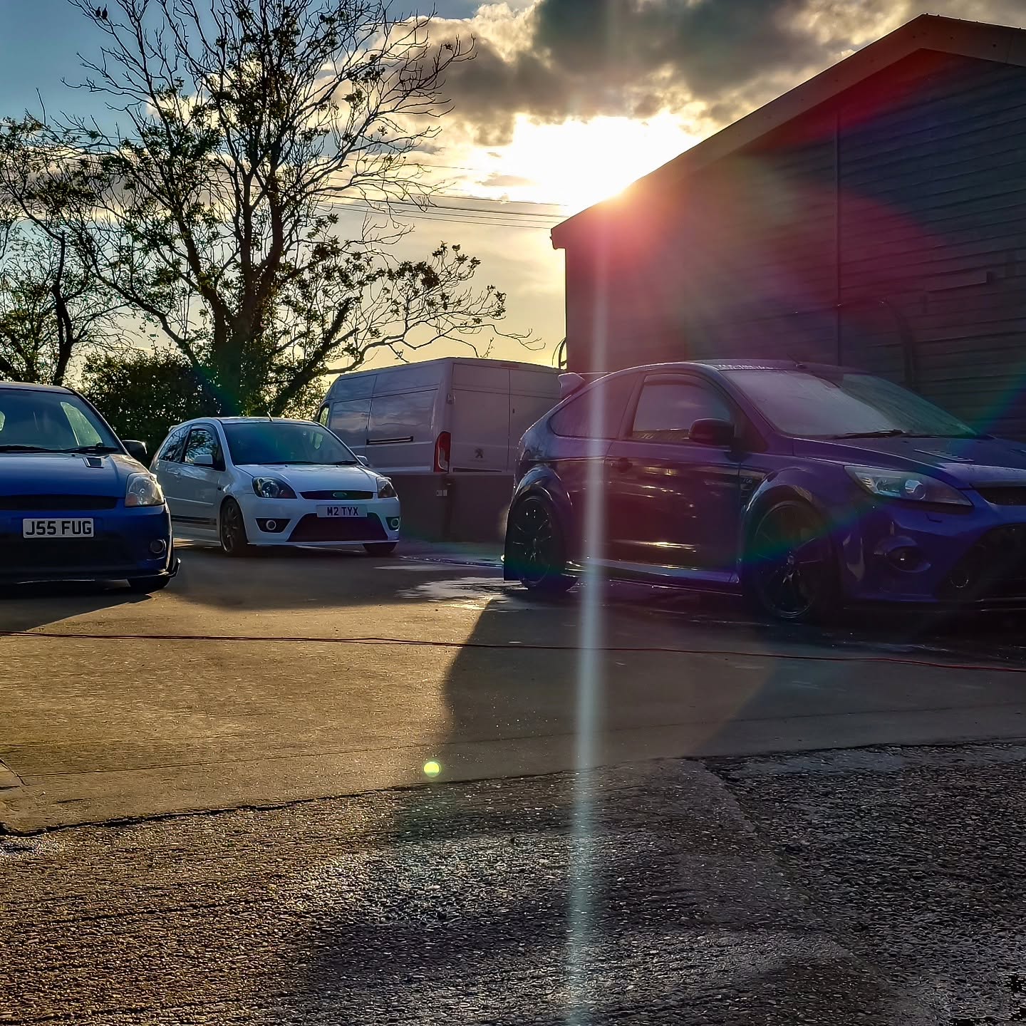 Customer cars lined up outside the workshop at sunset